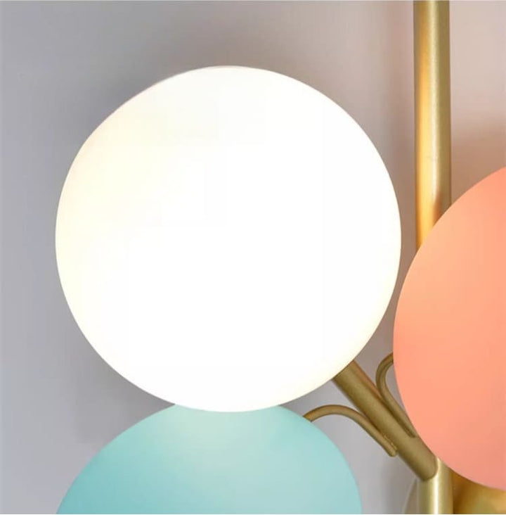 Gros plan sur un globe en verre opalin lumineux fixé à la structure dorée de la suspension