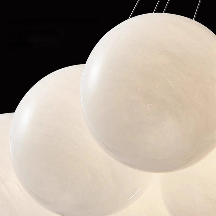 Gros plan sur les globes en verre opalin blanc à la texture délicate d'une suspension design contemporaine