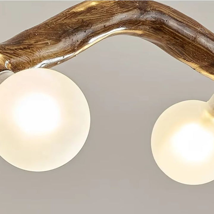 Détail de deux globes lumineux blancs sous une branche courbée effet bois, aux reliefs veinés et à l'esprit naturel.