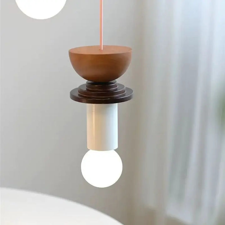 Gros plan sur une suspension totem en bois marron et teintes pastel avec ampoule globe apparente.