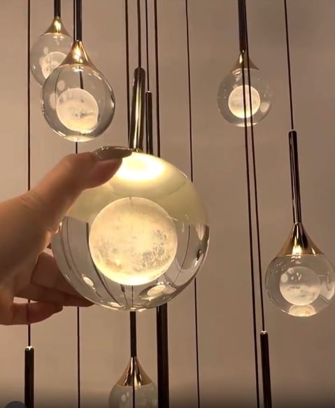 Gros plan sur une suspension en verre transparent à cœur opalin, finition dorée, style design élégant.