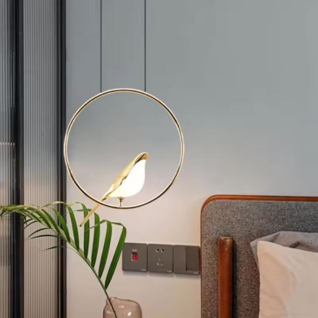 Lampe de chevet suspendue avec anneau doré et oiseau lumineux, parfaite pour une ambiance douce et poétique dans la chambre.