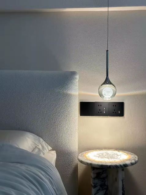 Lampe de chevet suspendu en goutte de verre cristallin et métal noir, lumière d’appoint élégante pour chambre au style contemporain.
