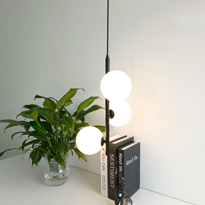 Lampe pendante LED moderne alliant structure métallique fine et globes opalescents.