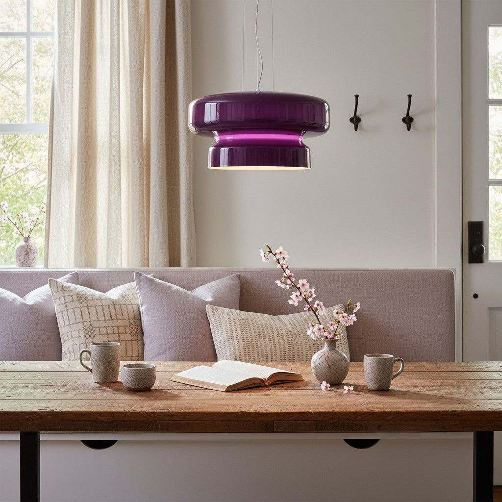 Lampe pendante en verre fumé violet au-dessus d'une table à manger et d'un banc en bois.