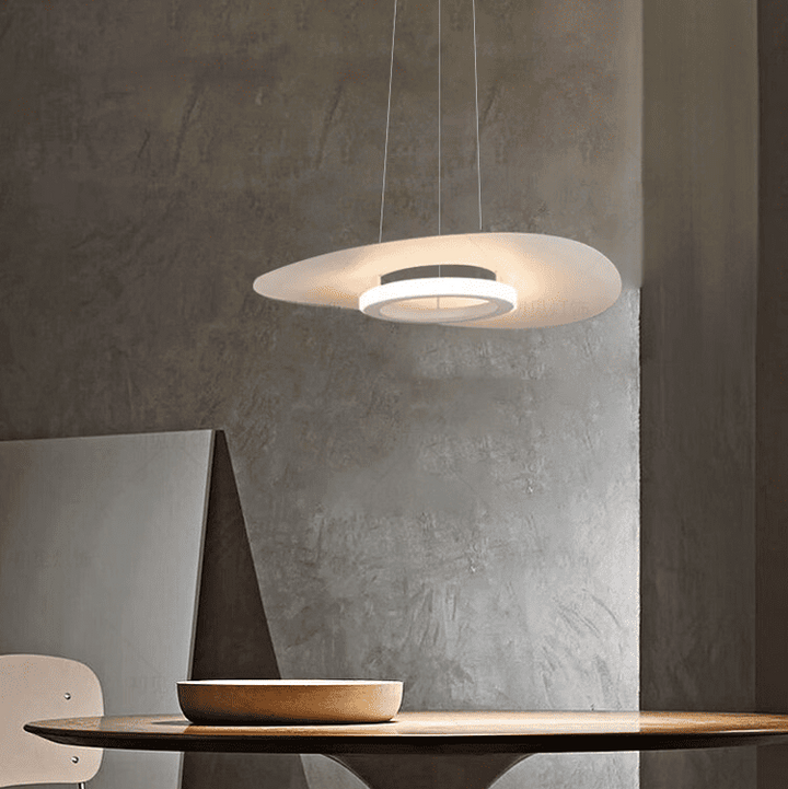 Lampe suspendue disque flottant diffusant une douce lumière dans un intérieur brut.