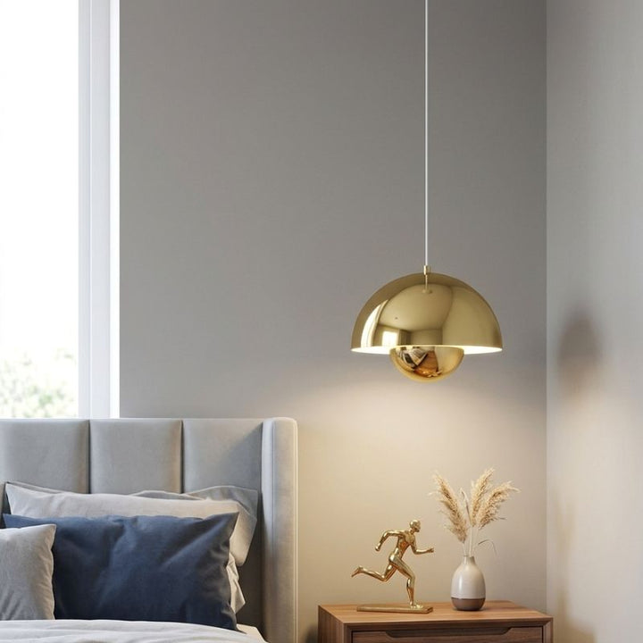 Lampe suspendue dorée diffusant une lumière chaleureuse dans une chambre au décor raffiné et apaisant.