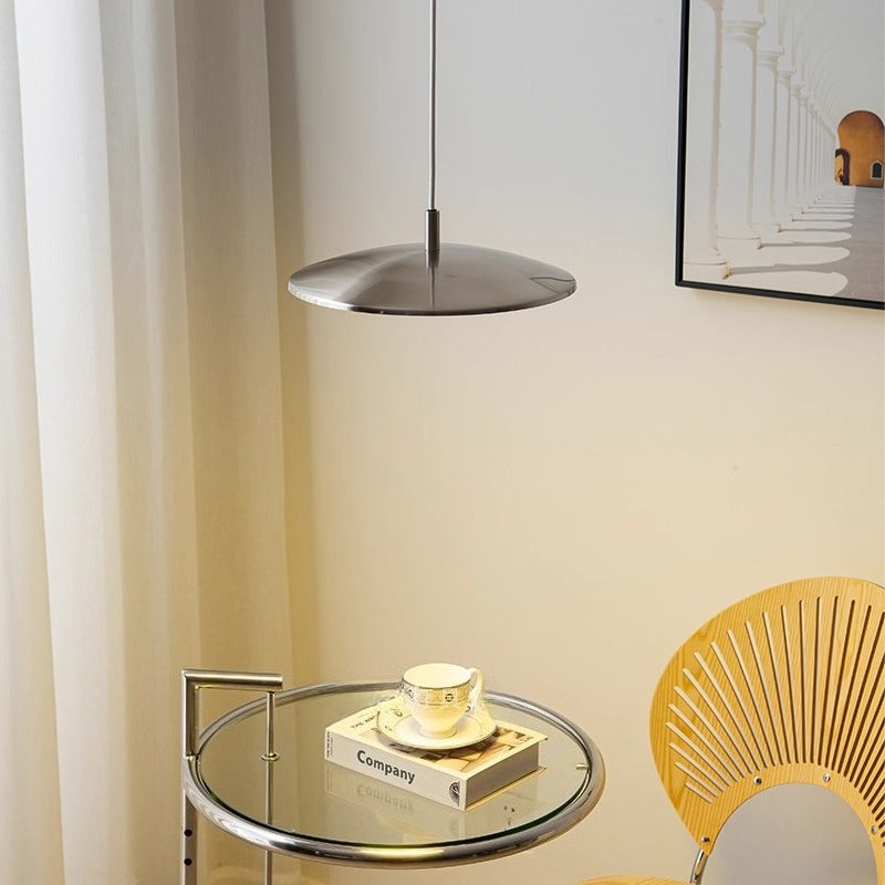 Suspension ronde en forme de disque au style scandinave suspendue au-dessus d'un petit coin salon chaleureux.