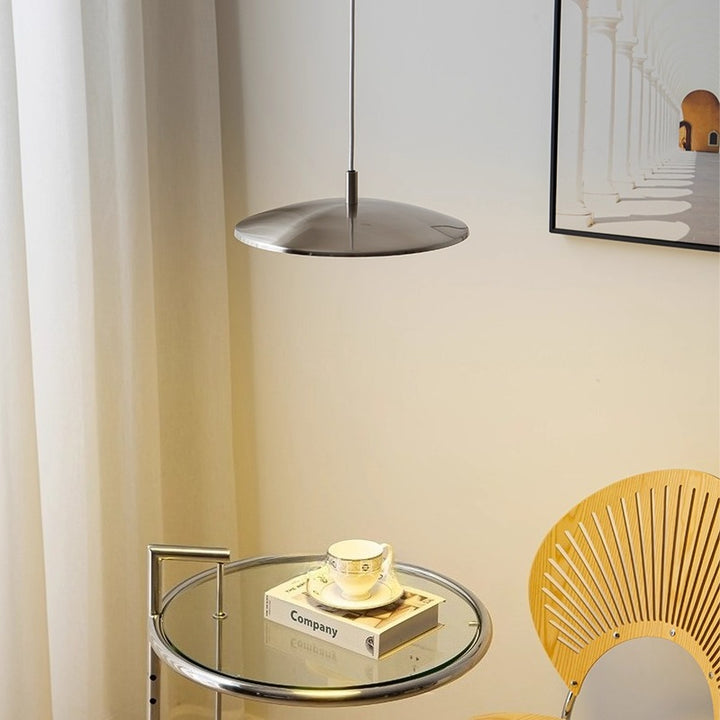 Suspension ronde en forme de disque au style scandinave suspendue au-dessus d'un petit coin salon chaleureux.