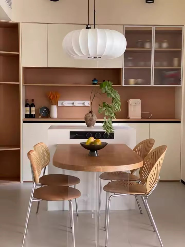 Lampe suspendue en tissu ivoire nervuré au-dessus d’une table, dans une cuisine au design organique et épuré