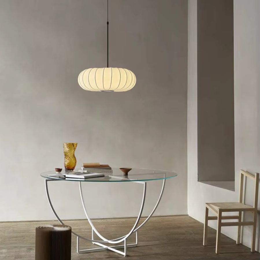 Lampe suspendue en tissu ivoire nervuré au-dessus d’une table, dans une ambiance japandi sobre et chaleureuse