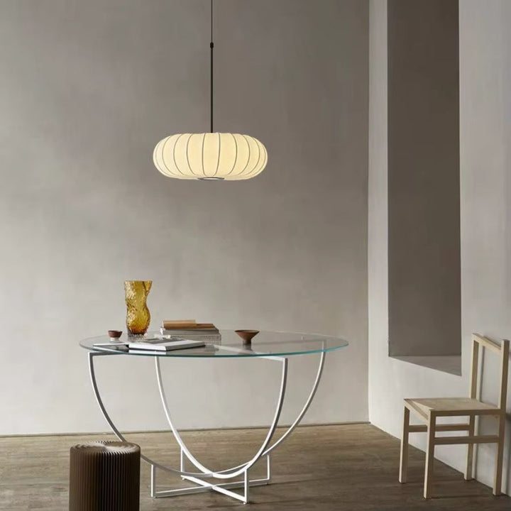 Lampe suspendue en tissu ivoire nervuré au-dessus d’une table, dans une ambiance japandi sobre et chaleureuse