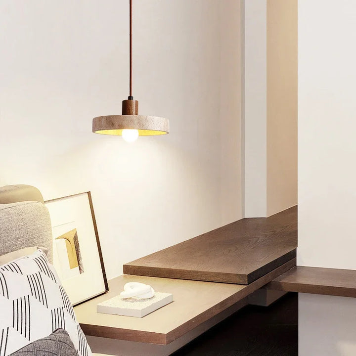 Lampe suspendue en travertin naturelle et bois foncé éclairant un espace bureau en bois dans un intérieur chaleureux.