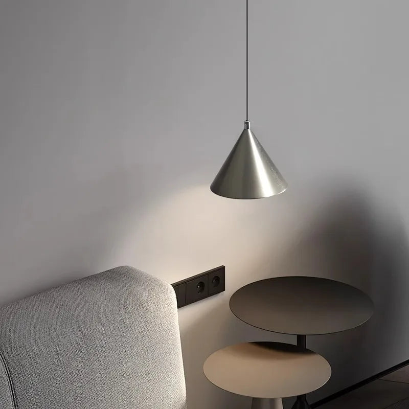 Lampe suspension utilisée comme liseuse élégante au-dessus d'un fauteuil, parfaite pour un coin lecture cosy.