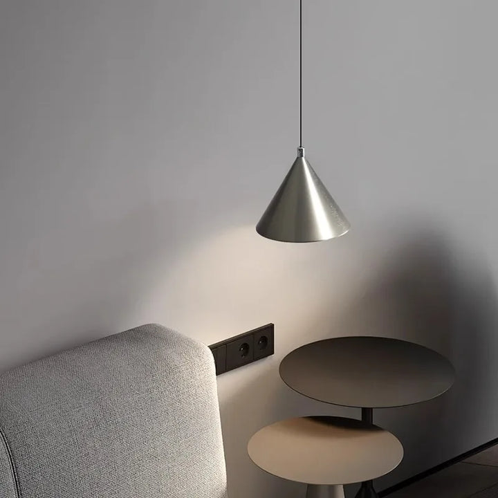 Lampe suspension utilisée comme liseuse élégante au-dessus d'un fauteuil, parfaite pour un coin lecture cosy.