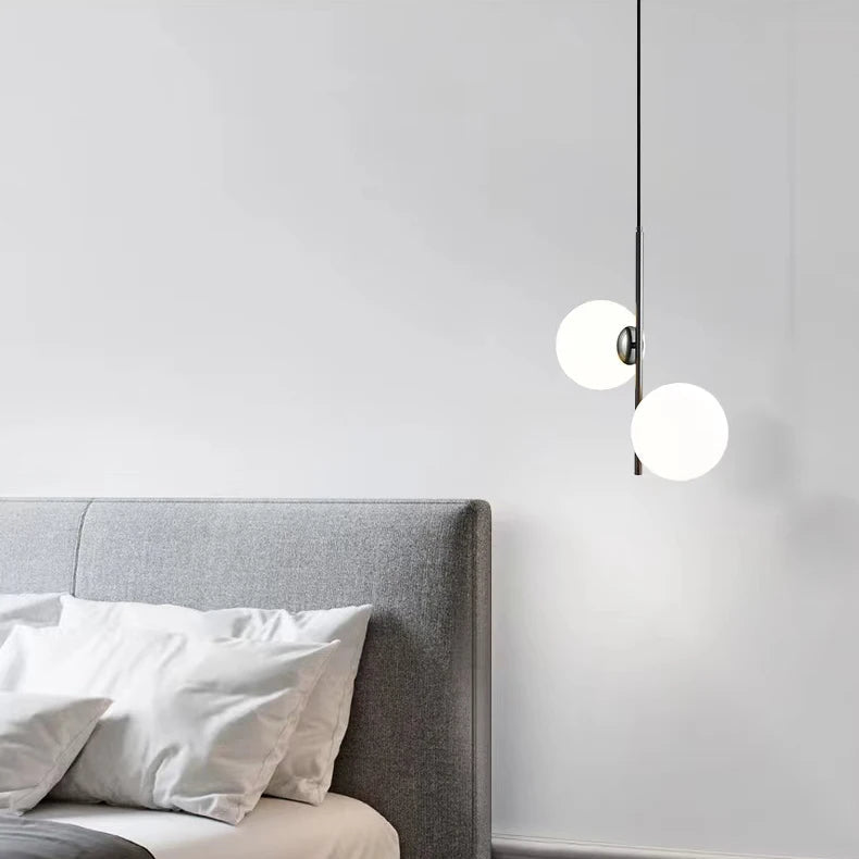 Lampe suspension minimaliste à boules lumineuses suspendue près d'une tête de lit grise.