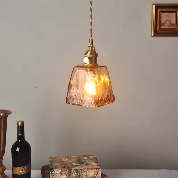 Luminaire aux reflets ambrés et verre sculpté, suspendu au-dessus d’une table dans une ambiance rétro chaleureuse