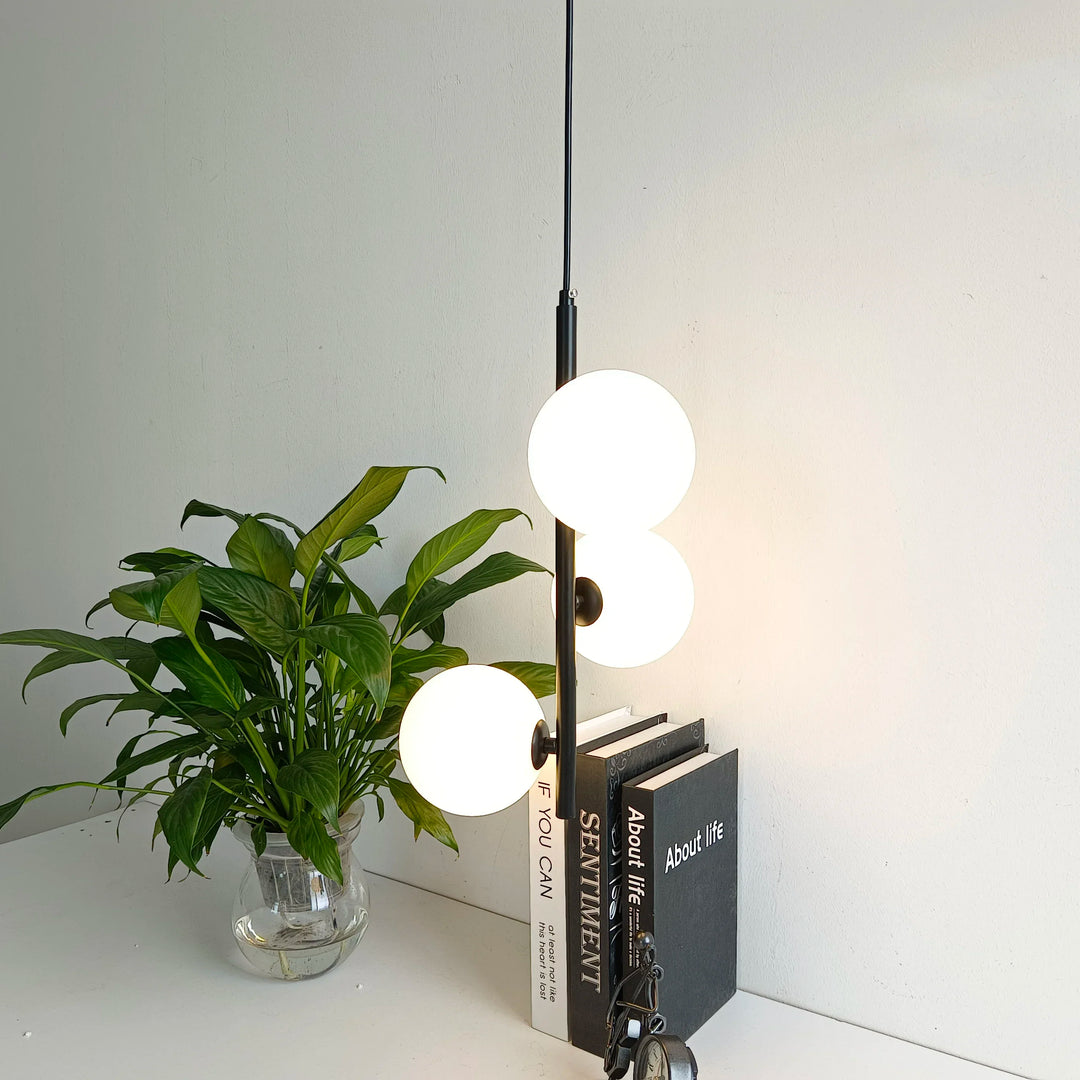 Luminaire style art déco avec boules en verre, mis en scène avec des plantes et des livres.