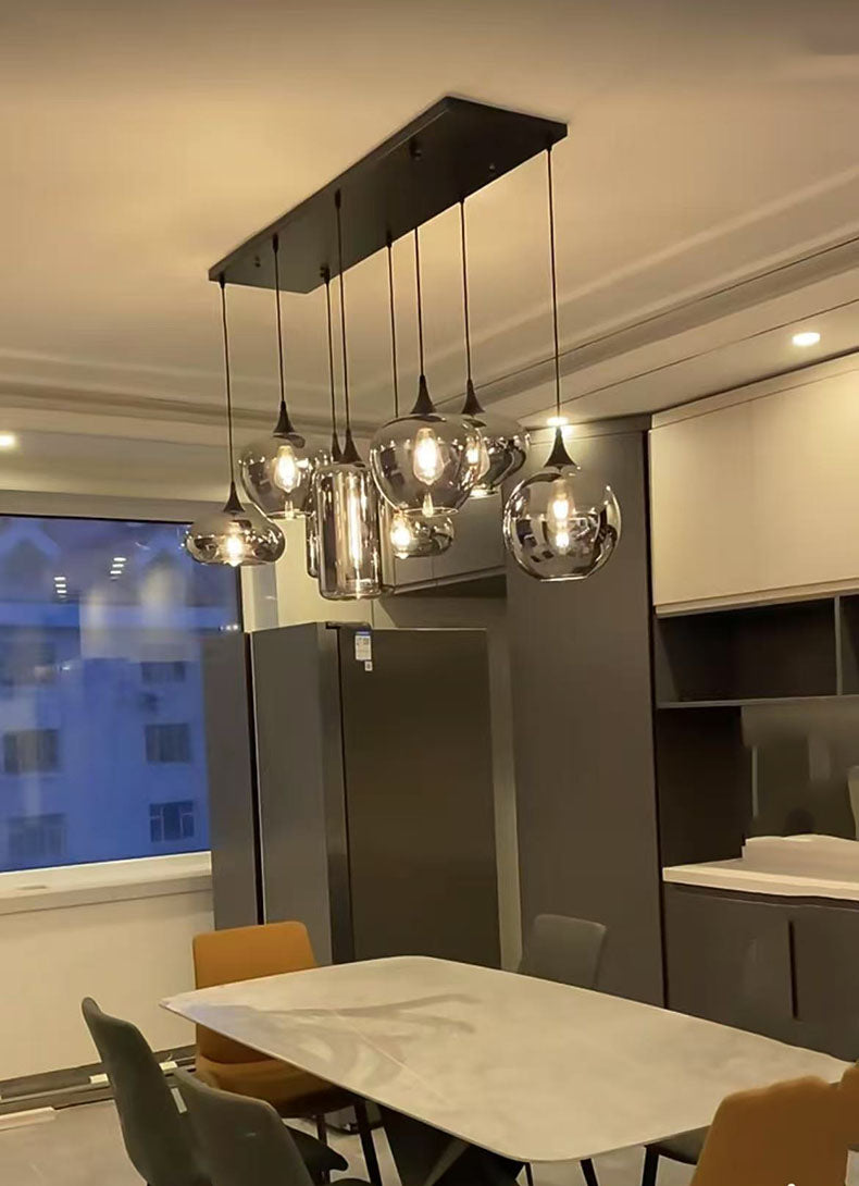 Luminaire barre à plusieurs abat-jours suspendus en verre fumé intégré dans la décoration lumineuse d'un appartement contemporain.