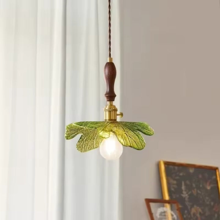 Éclairage suspendu aux feuilles de verre vert nervuré et détails en bois de noyer dans un esprit botanique vintage