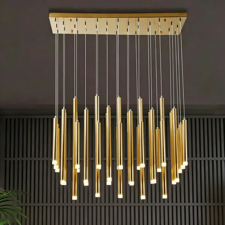 Luminaire cascade moderne aux tubes dorés scintillant dans une pièce à l'ambiance feutrée.