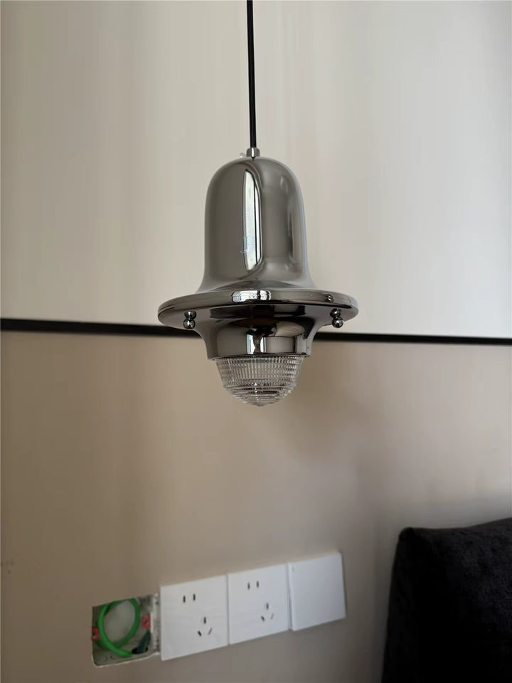 Vue rapprochée du luminaire cloche en métal chromé avec diffuseur en verre strié, au style rétro industriel, en guise de lampe de chevet suspendu