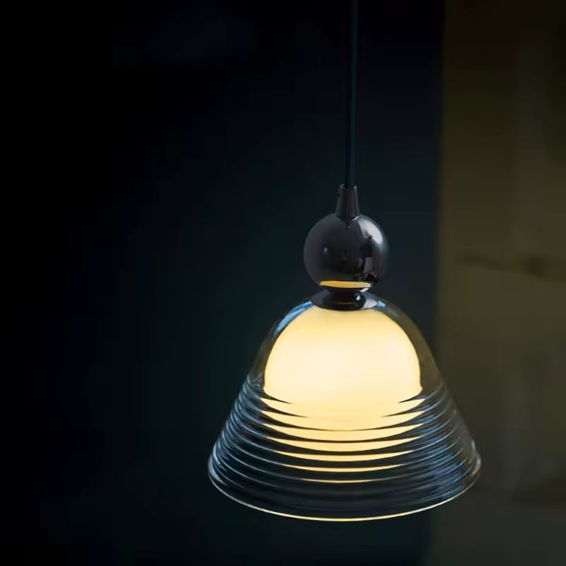 Luminaire en verre soufflé strié avec globe opalin lumineux, diffusant une lumière chaude au style rétro contemporain