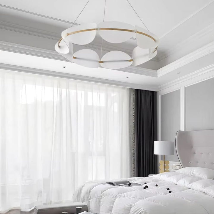 Luminaire en couronne à pétales blancs et cercle doré, suspendu dans une chambre au style élégant et contemporain