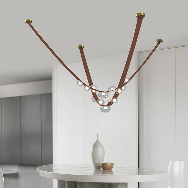 Élégant luminaire suspendu en cuir et sphères lumineuses disposé au-dessus d'une table ronde épurée.