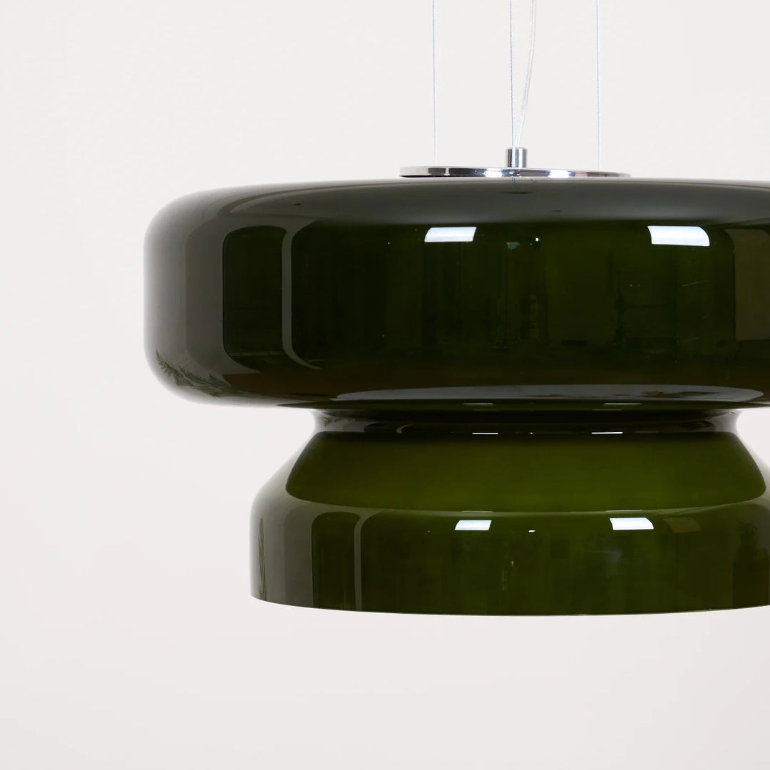 Gros plan sur un luminaire au design space age en verre fumé vert sur fond neutre et minimaliste.