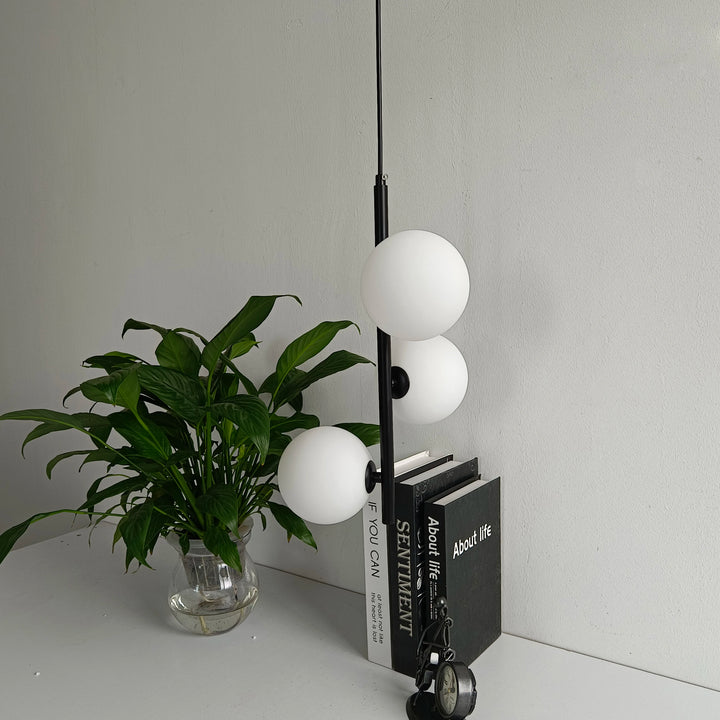 Luminaire design avec sphères blanches disposées de façon asymétrique pour un style unique.
