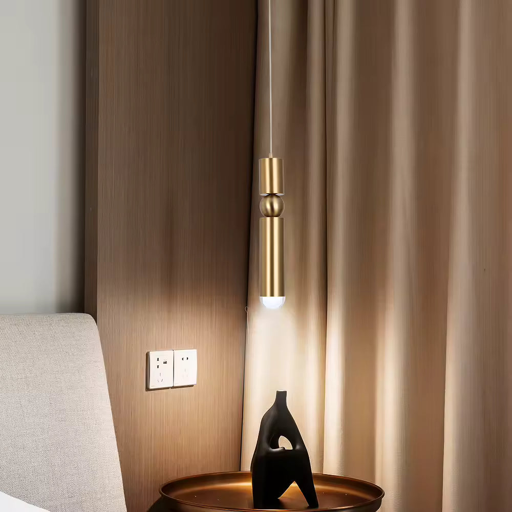 Luminaire doré allongé à sphère centrale, installé en chevet dans une chambre moderne au style épuré