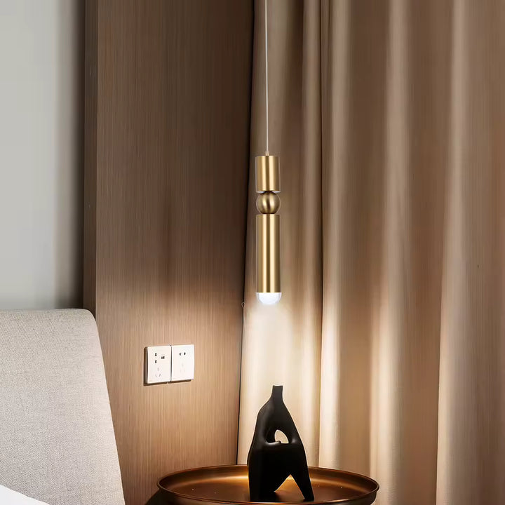 Luminaire doré allongé à sphère centrale, installé en chevet dans une chambre moderne au style épuré