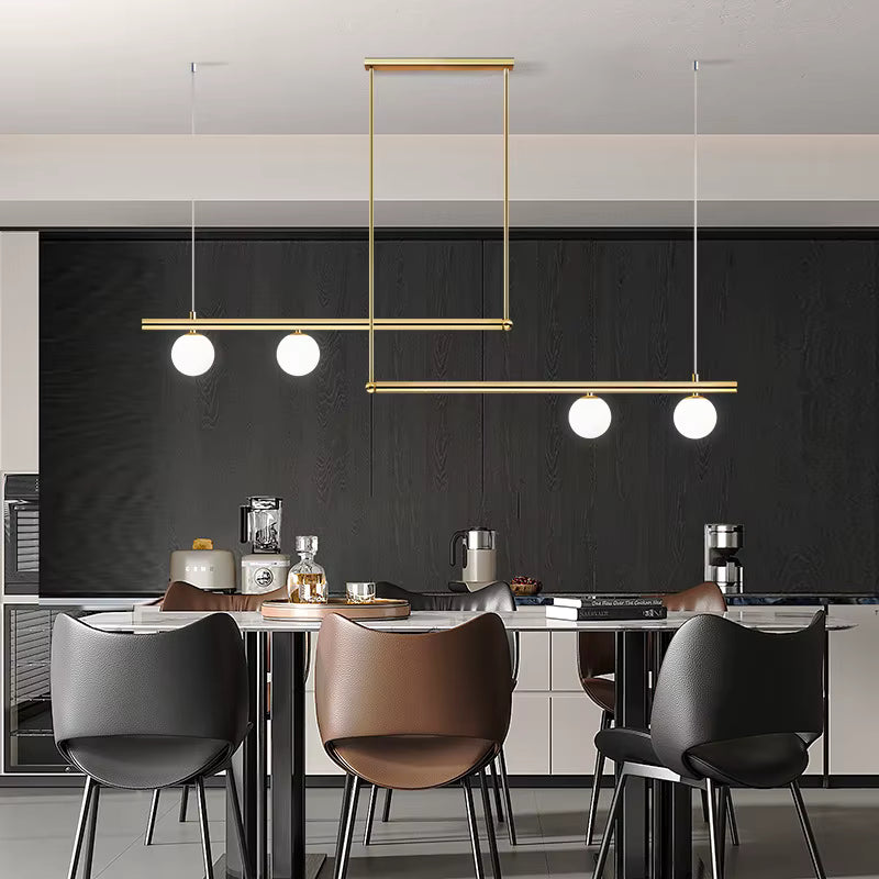 Luminaire doré à lignes décalées et quatre globes opalins, structurant une cuisine contemporaine au style graphique