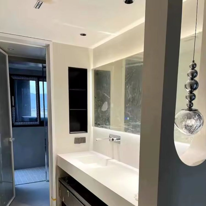 Près du miroir, ce luminaire à sphères chromées et globe texturé apporte une touche moderne et décorative