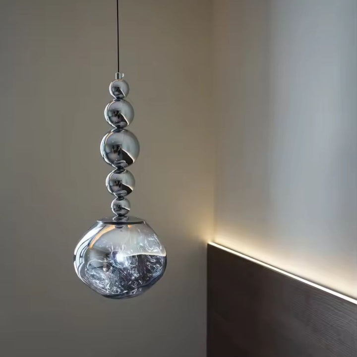 Avec ses cinq sphères chromées et son globe transparent texturé, ce luminaire apporte une note élégante à la chambre