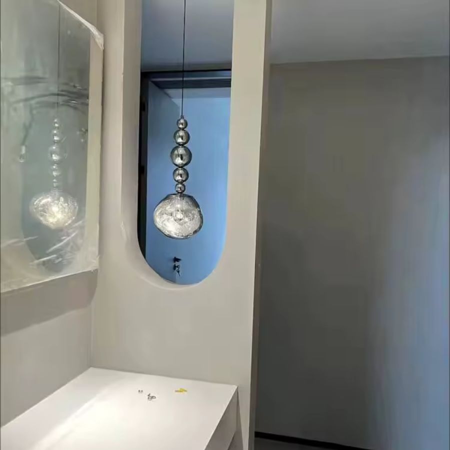Dans une entrée contemporaine, ce luminaire à sphères chromées révèle un globe texturé aux reflets cristallins