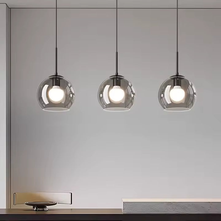 Alignés avec sobriété, trois globes en verre fumé soulignent le style minimaliste de ce luminaire noir