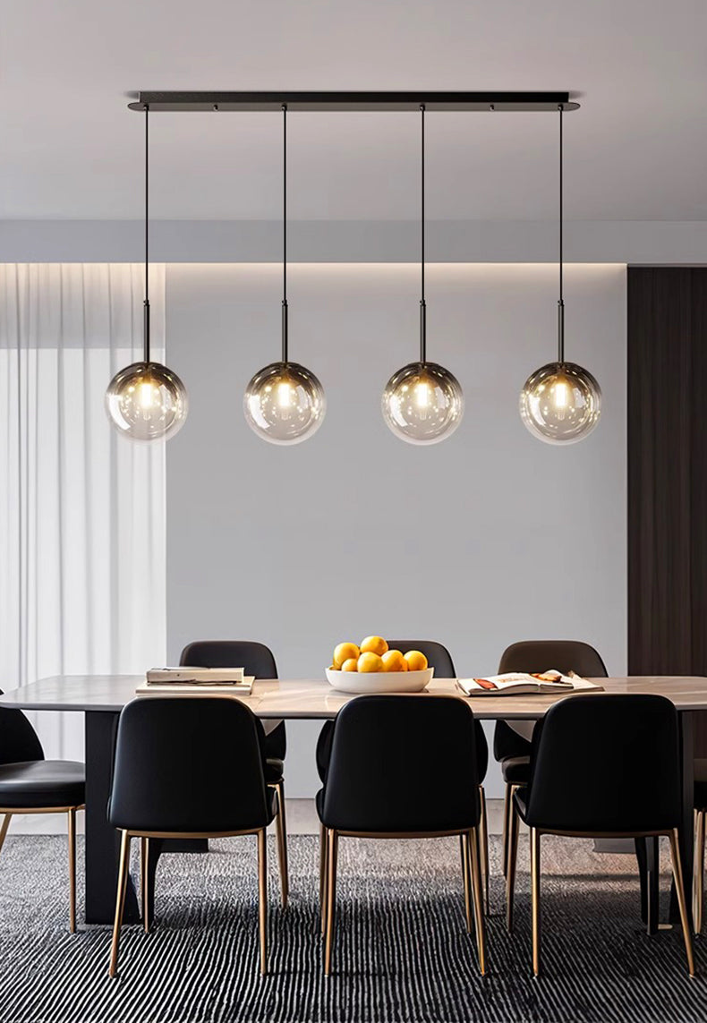 Long luminaire d'intérieur à globes en verre suspendus structurant l'espace d'une cuisine contemporaine.