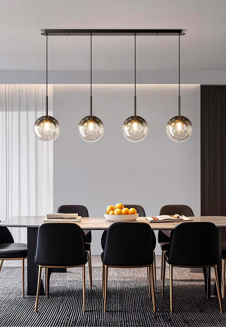 Long luminaire d'intérieur à globes en verre suspendus structurant l'espace d'une cuisine contemporaine.