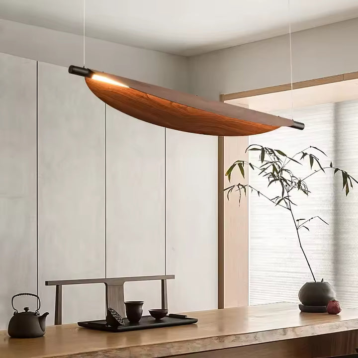 Au-dessus d’une table en bois, ce luminaire courbe effet bois crée une ambiance japandi, zen et contemporaine