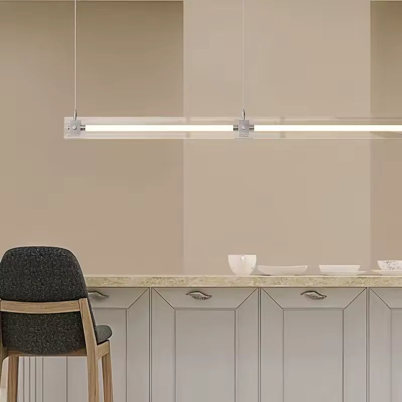 Éclairage linéaire en verre et acier inoxydable, suspendu au-dessus d’un comptoir dans un intérieur minimaliste