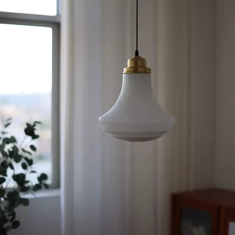 Luminaire en opaline blanche nervurée à silhouette évasée, suspendu près d’une fenêtre dans un intérieur rétro chic