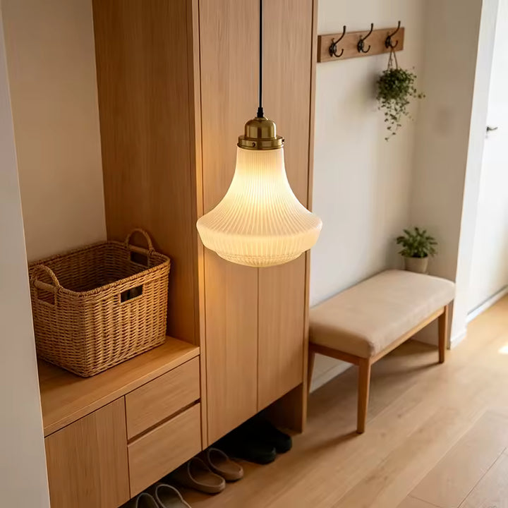 Luminaire en opaline nervurée à finition laiton, apportant une lumière chaleureuse dans une entrée au style naturel
