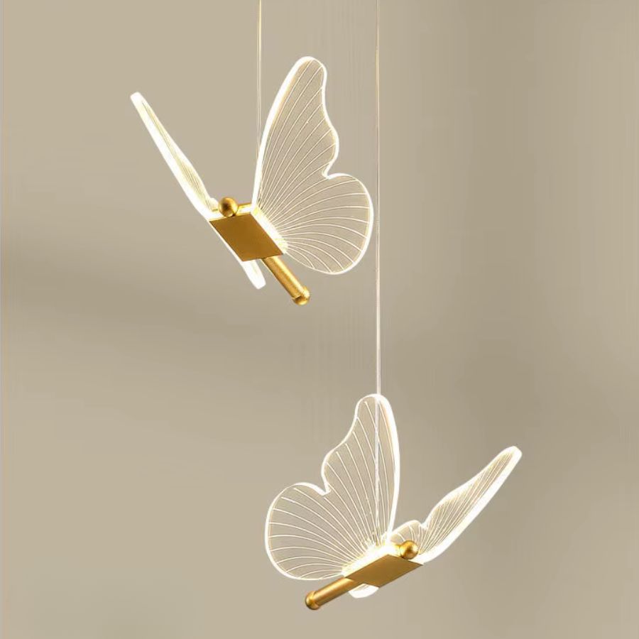 Deux papillons aux ailes transparentes et dorées forment un luminaire suspendu délicat au style aérien