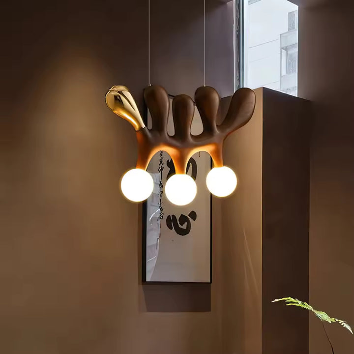 Dans un décor moderne, le luminaire en bois foncé et touche de laiton associe trois globes blancs à une silhouette sculpturale au style luxueux
