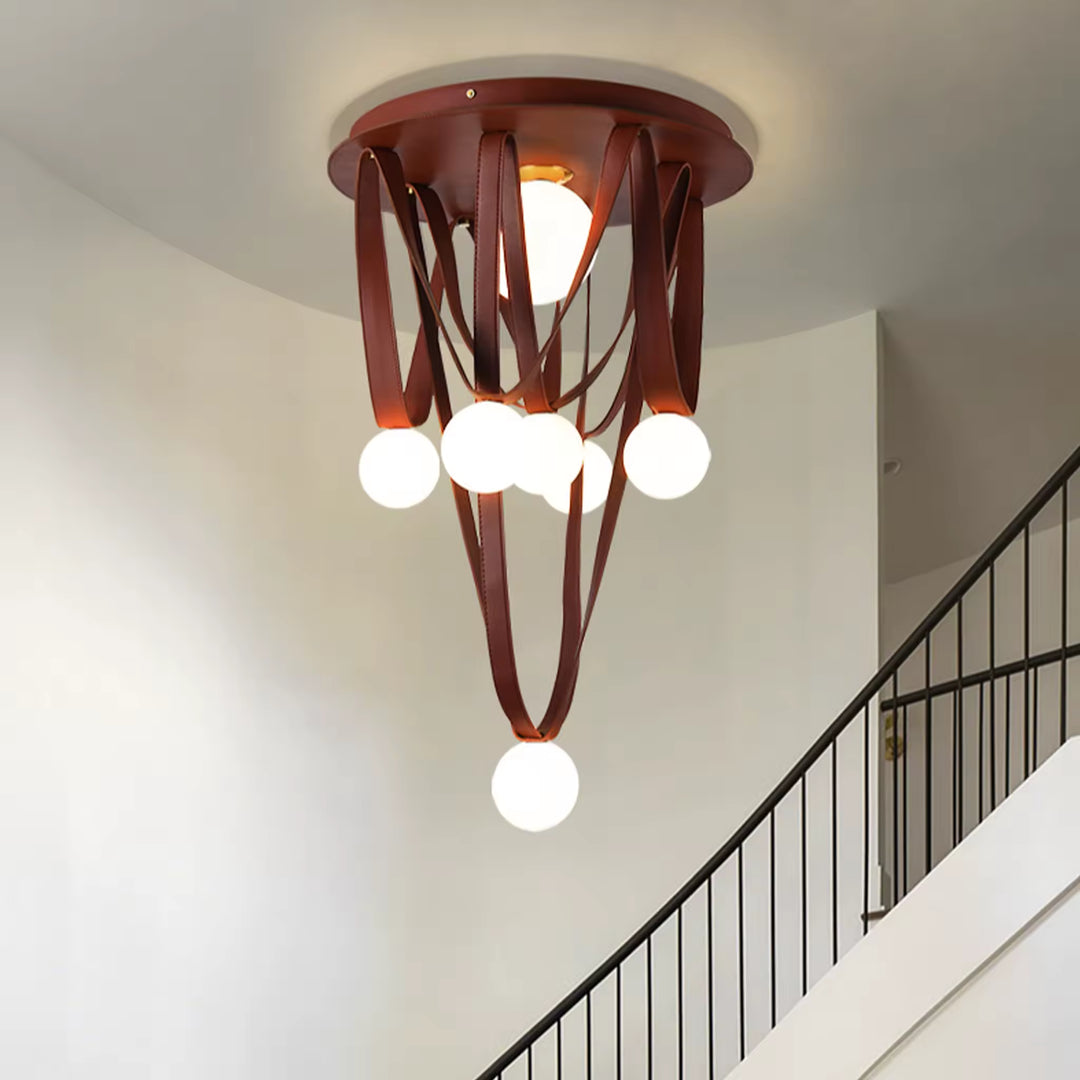 Dans une cage d’escalier, ce luminaire sculptural associe lanières de cuir brun et globes opalins en cascade.