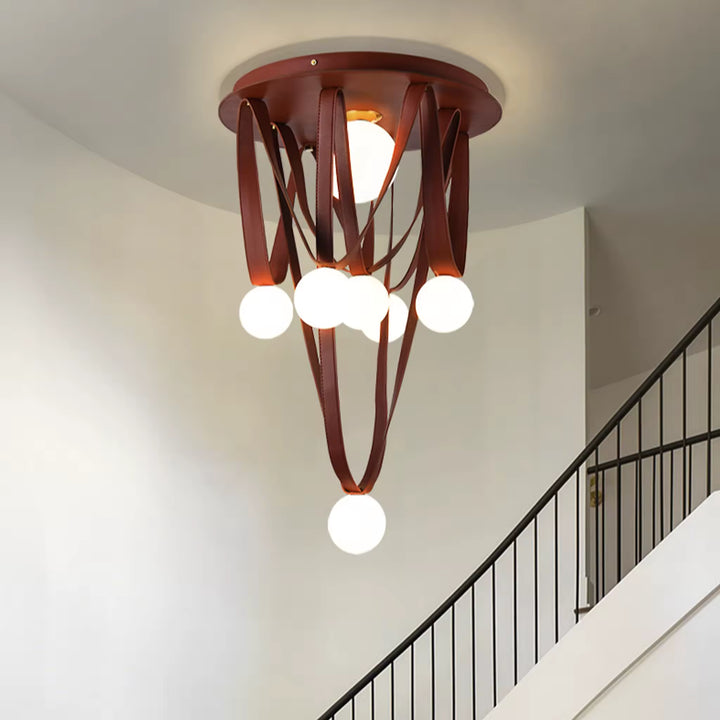 Dans une cage d’escalier, ce luminaire sculptural associe lanières de cuir brun et globes opalins en cascade.