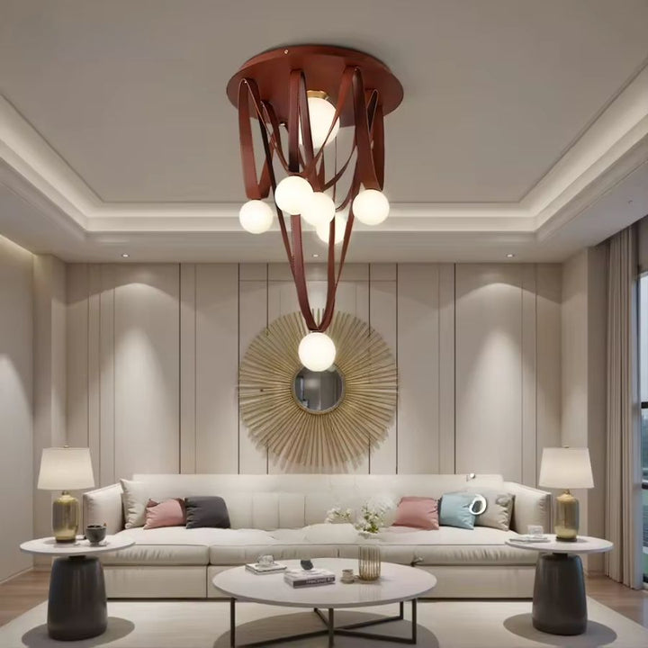 Dans un salon élégant, ce luminaire sculptural en cuir brun et globes opalins crée une présence artistique et chaleureuse.