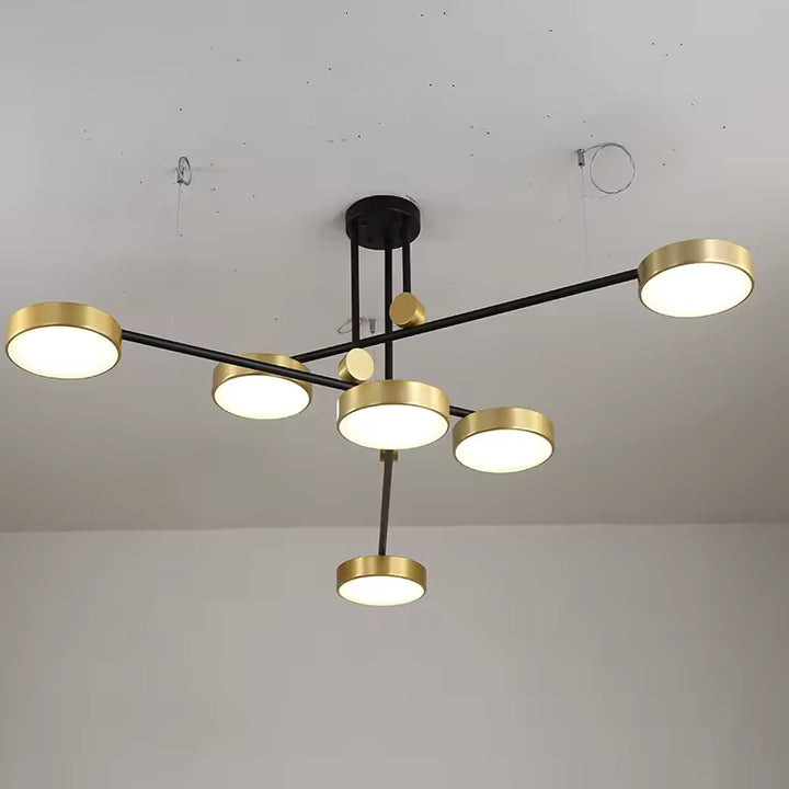 Composition sculpturale de disques dorés sur bras noirs croisés, pour un luminaire moderne à l’allure graphique.